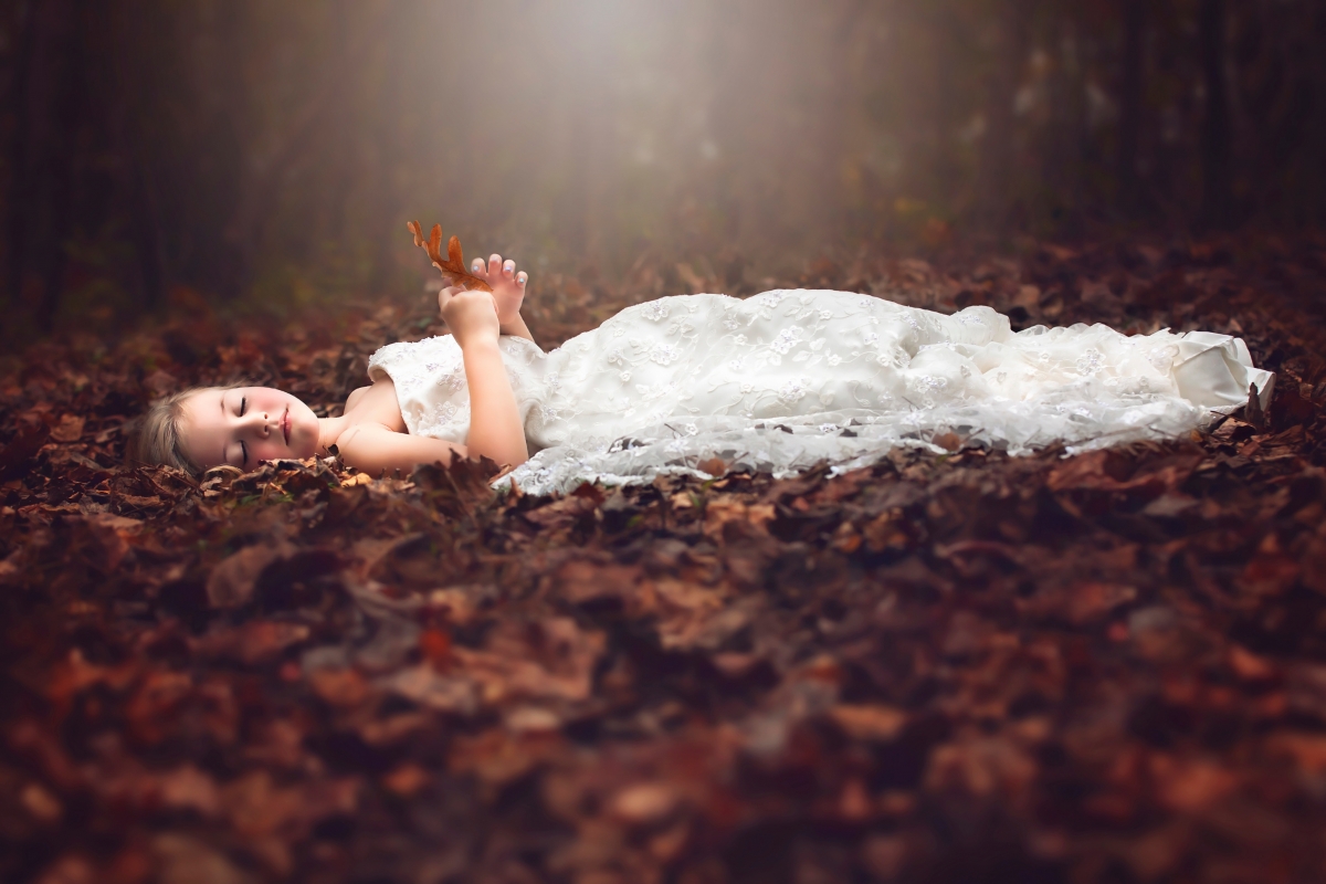 Little sleeping on leaves in forest autumn