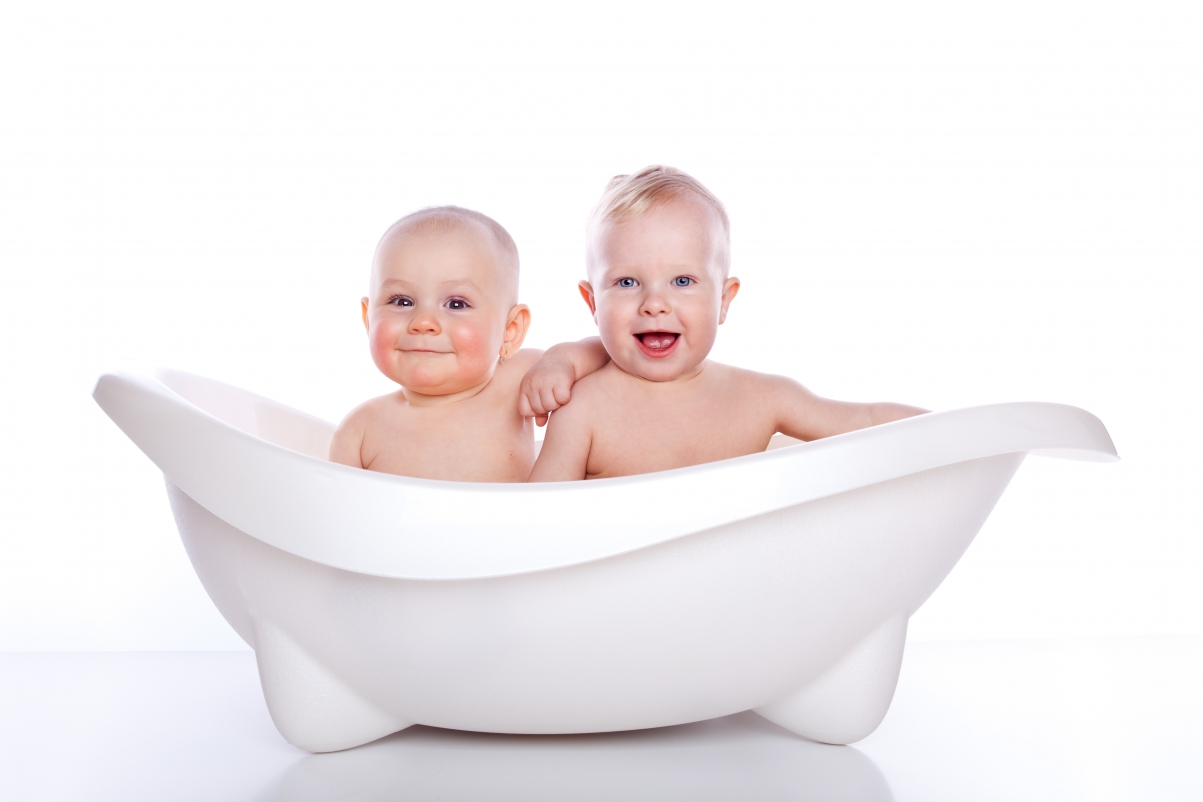 Two baby kids smiling taking a bath